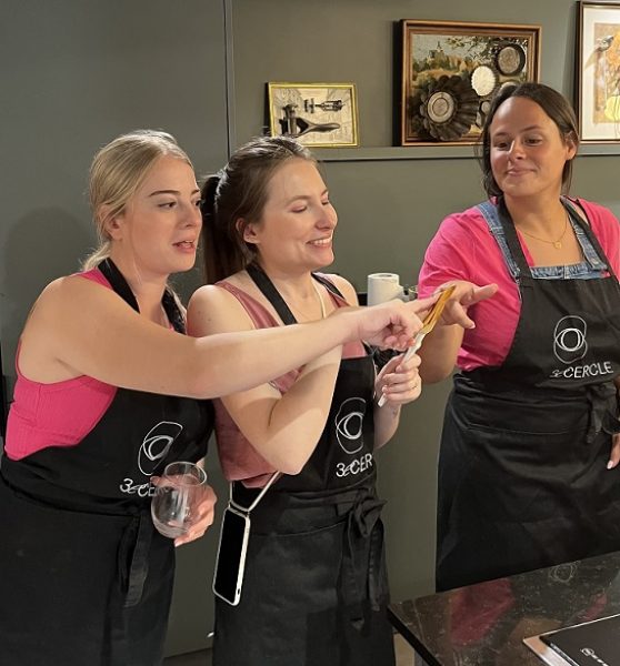 Trois femmes souriantes lors d'un cours de cuisine spécial EVJF